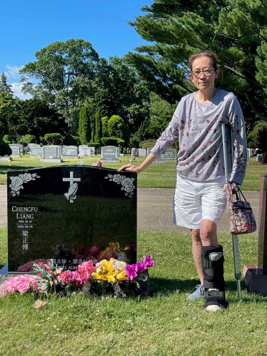 A family member standing beside a completed black granite memorial at a cemetery