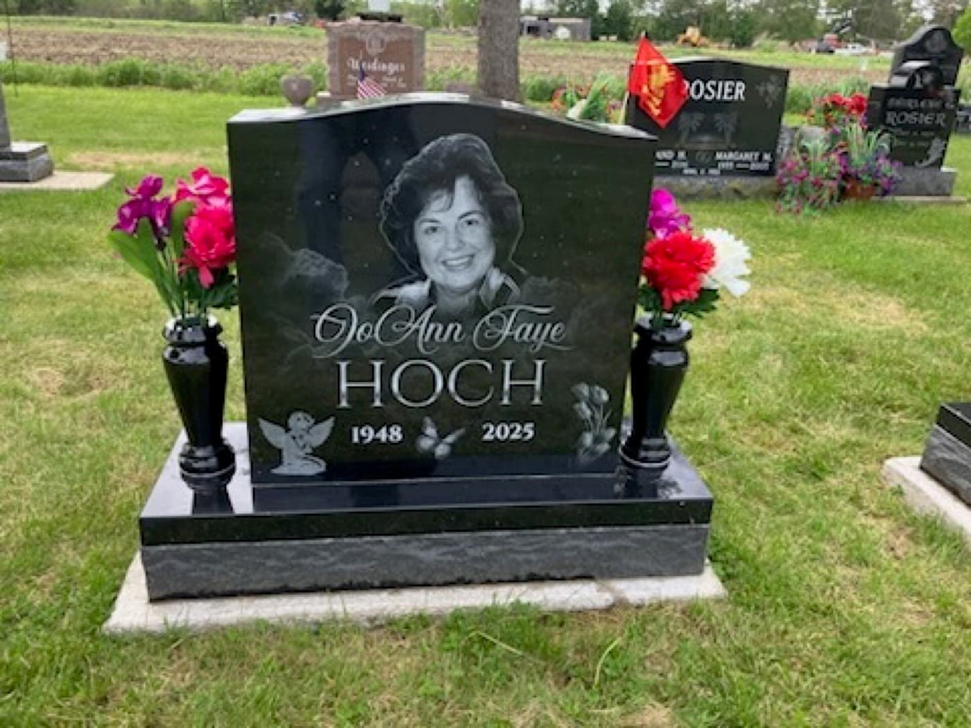 Upright headstone for OoAnn Faye Hoch installed in a cemetery — angel motif with fresh-cut flowers in a bronze vase at the base