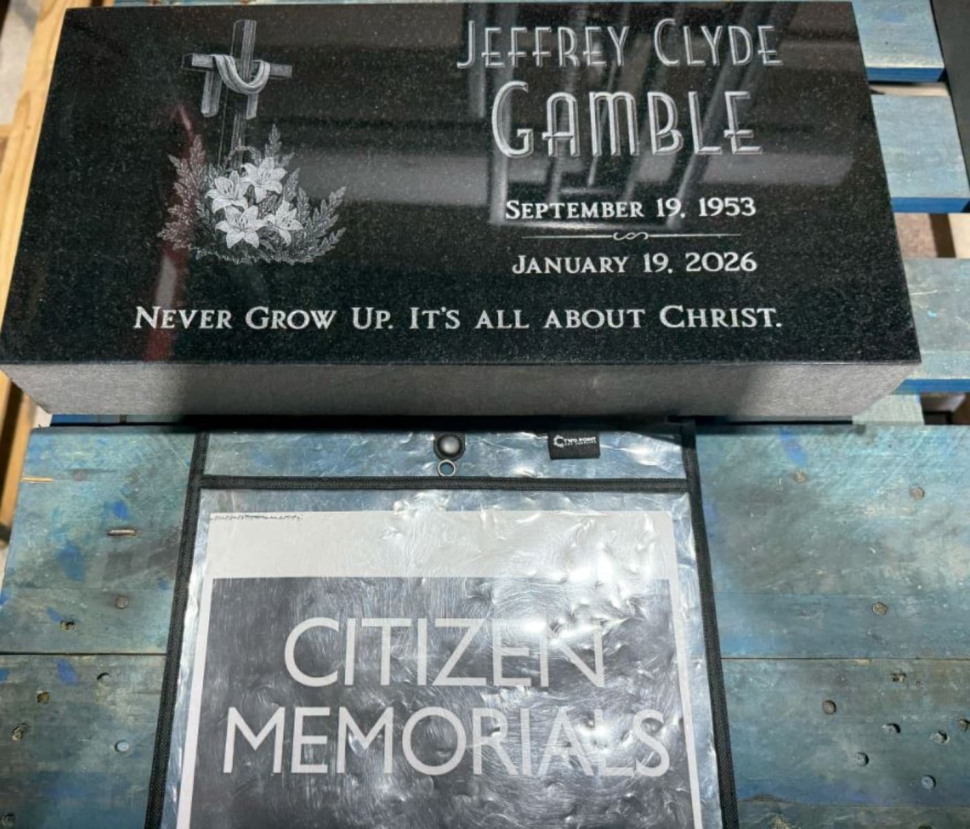 Black granite flat marker for Jeffrey Clyde Gamble — cross with lily motif and clean typographic name and dates inscription, no portrait