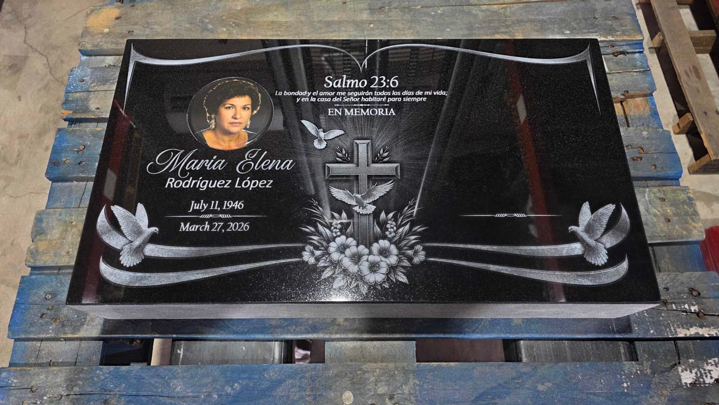 Detailed black granite memorial with a book, cross, doves, and floral engraving
